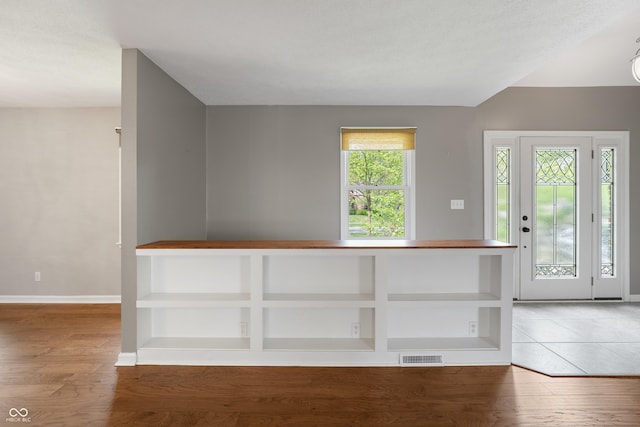 foyer entrance with baseboards, visible vents, and light wood finished floors