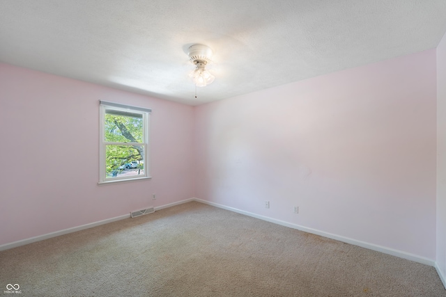 carpeted empty room with visible vents, a ceiling fan, and baseboards