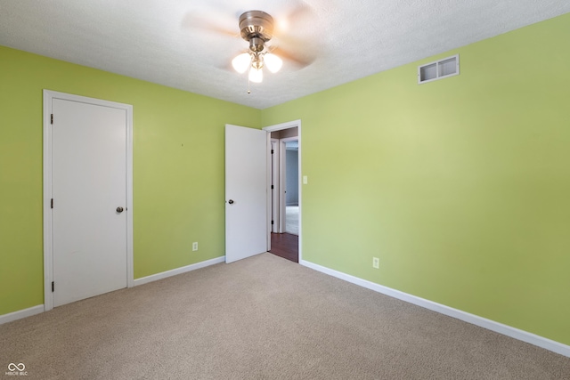 unfurnished bedroom with baseboards, carpet, a ceiling fan, and visible vents