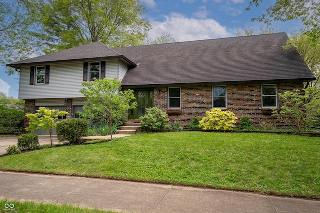 tri-level home featuring brick siding, a garage, a front lawn, and roof with shingles