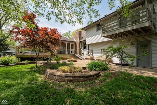 back of house featuring a balcony, a deck, a sunroom, a patio area, and a yard