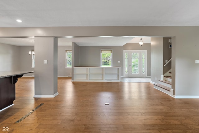 unfurnished living room featuring baseboards, recessed lighting, stairs, and hardwood / wood-style floors