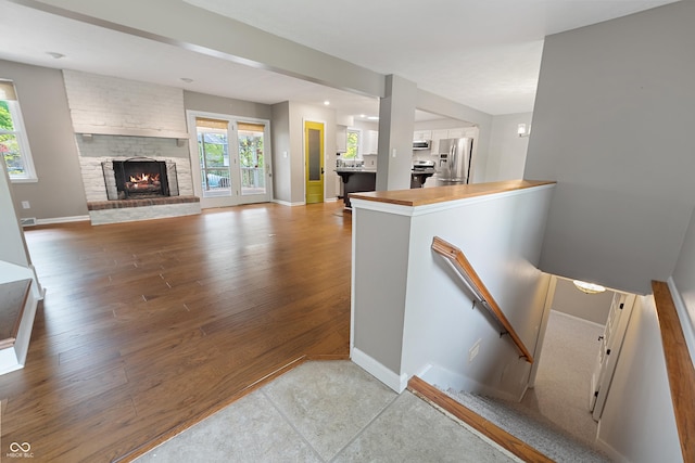 stairs featuring a brick fireplace, baseboards, and wood finished floors