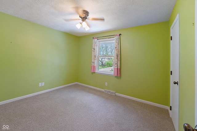 carpeted spare room featuring a ceiling fan, a textured ceiling, visible vents, and baseboards