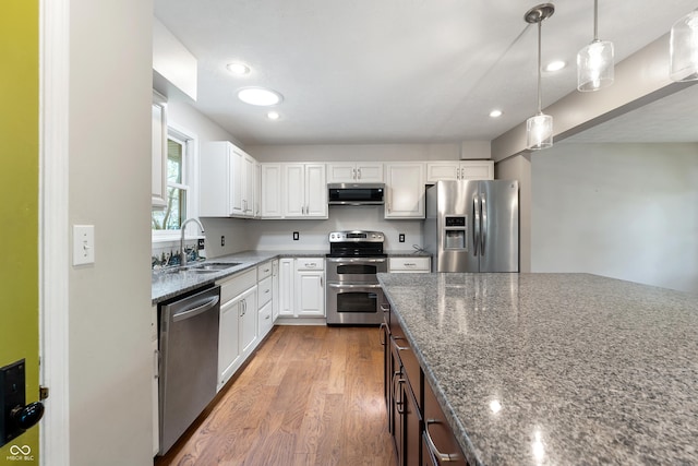 kitchen with light wood-style floors, white cabinets, a sink, dark stone countertops, and stainless steel appliances