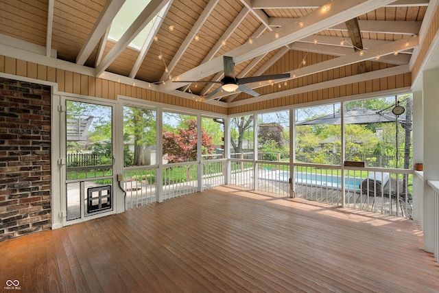 unfurnished sunroom with ceiling fan, plenty of natural light, and beam ceiling