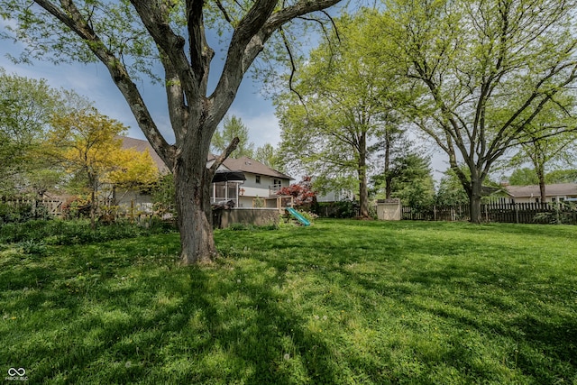 view of yard featuring a playground, a storage unit, an outdoor structure, and a fenced backyard