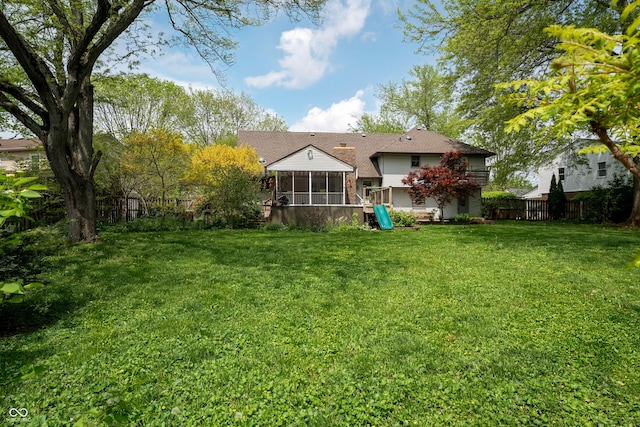 back of house featuring fence, a yard, and a sunroom
