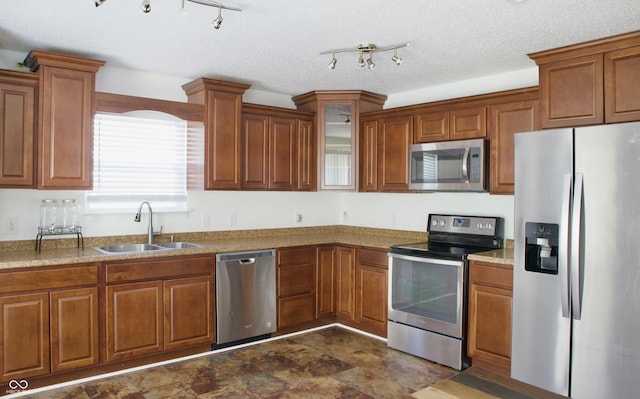 5236 Skipping Stone Dr, Indianapolis, IN 46237 - kitchen featuring a sink, glass insert cabinets, brown cabinetry, stone finish floor, and appliances with stainless steel finishes
