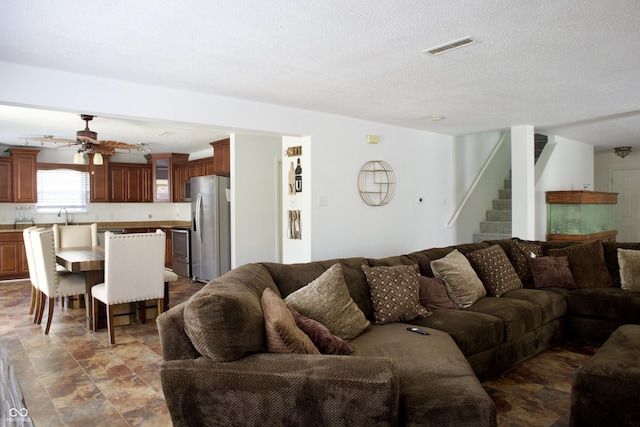 5236 Skipping Stone Dr, Indianapolis, IN 46237 - living room with stone finish floor, a textured ceiling, stairway, visible vents, and a ceiling fan