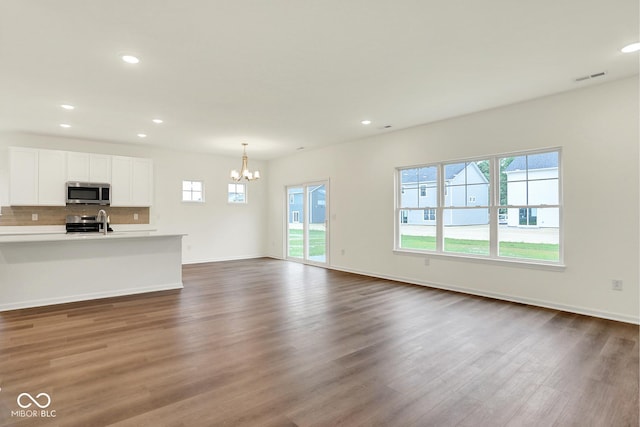 2712 Glade Ave, Plainfield, IN 46168 - unfurnished living room featuring plenty of natural light, a chandelier, dark wood finished floors, baseboards, and recessed lighting