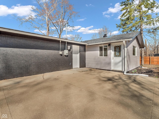 back of house with fence, a patio area, and a shingled roof