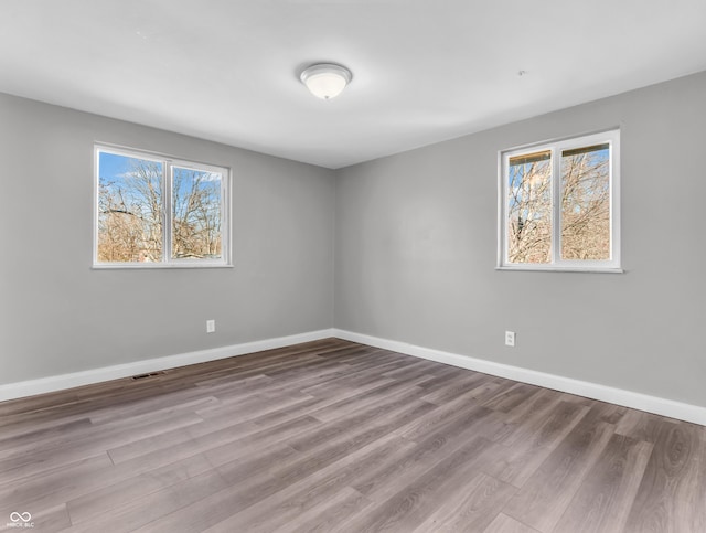 spare room featuring visible vents, baseboards, and wood finished floors
