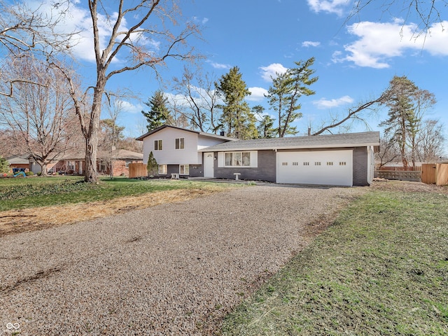 split level home with a garage, gravel driveway, a front yard, and fence