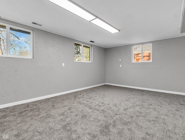 basement featuring a wealth of natural light, carpet flooring, visible vents, and baseboards
