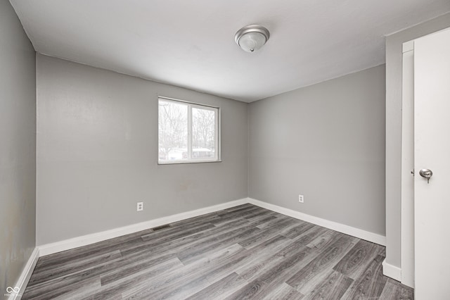 unfurnished room with visible vents, baseboards, and wood finished floors