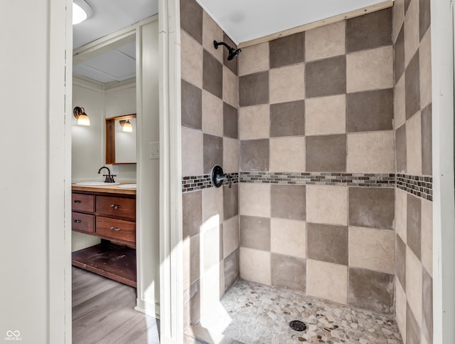 bathroom with a tile shower, wood finished floors, and vanity