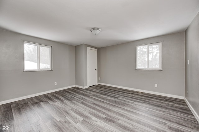 spare room with baseboards, wood finished floors, and a healthy amount of sunlight