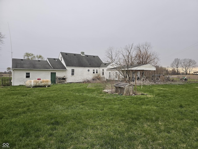 back of property featuring a lawn and fence