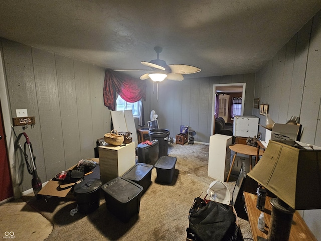 interior space with wooden walls, carpet flooring, and a ceiling fan