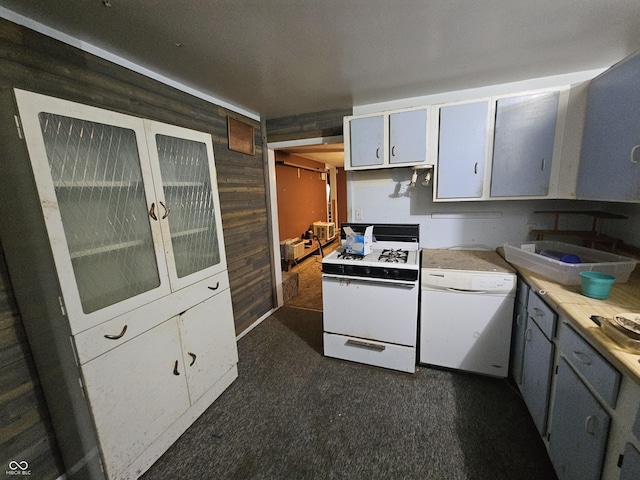 kitchen with white appliances, glass insert cabinets, light countertops, dark carpet, and wood walls