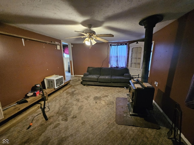 carpeted living area with a textured ceiling, a wood stove, a ceiling fan, and a wall unit AC