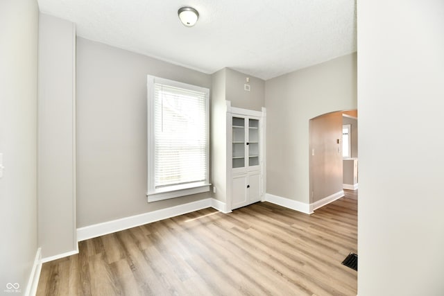106 S Wayburn St, Indianapolis, IN 46229 - spare room featuring arched walkways, wood finished floors, visible vents, and baseboards