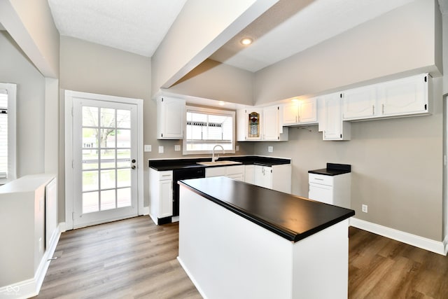 106 S Wayburn St, Indianapolis, IN 46229 - kitchen with a sink, dark countertops, light wood-style floors, white cabinetry, and dishwashing machine