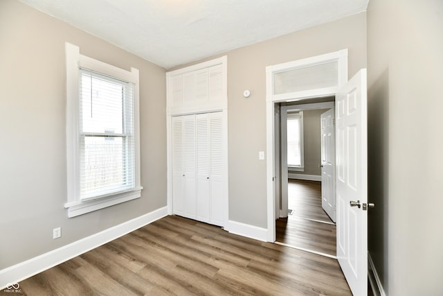 106 S Wayburn St, Indianapolis, IN 46229 - unfurnished bedroom featuring baseboards, multiple windows, wood finished floors, and a closet