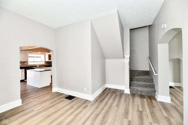 106 S Wayburn St, Indianapolis, IN 46229 - additional living space with arched walkways, light wood finished floors, baseboards, and a sink