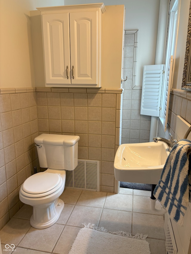 bathroom with tile patterned floors, a sink, wainscoting, tile walls, and visible vents