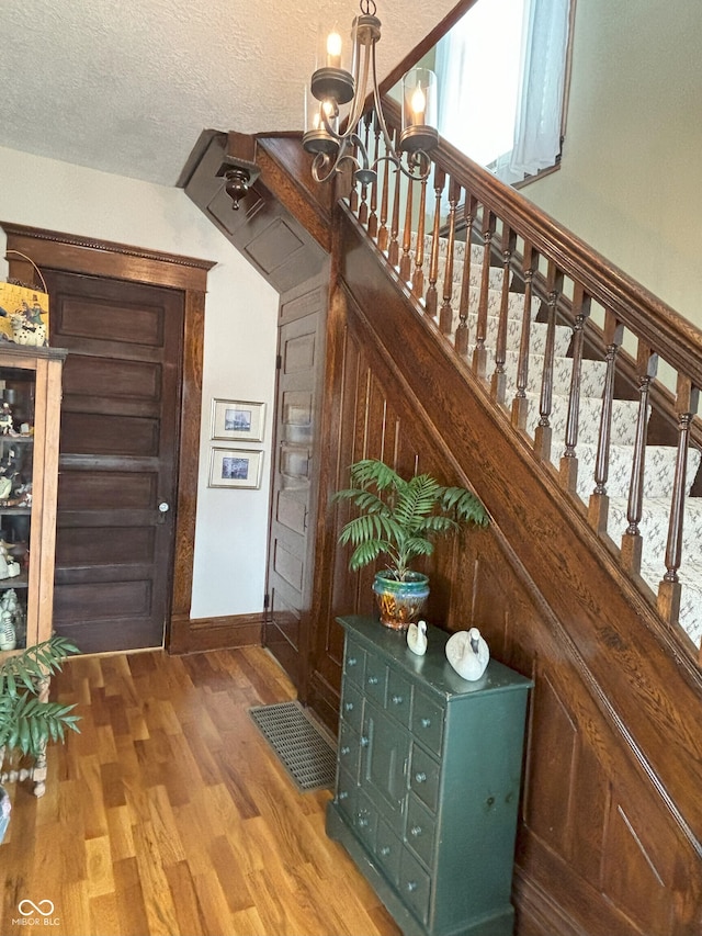 interior space featuring wood finished floors, a textured ceiling, baseboards, and an inviting chandelier