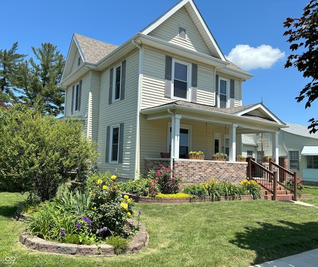 view of front of property featuring brick siding, a front lawn, roof with shingles, and covered porch