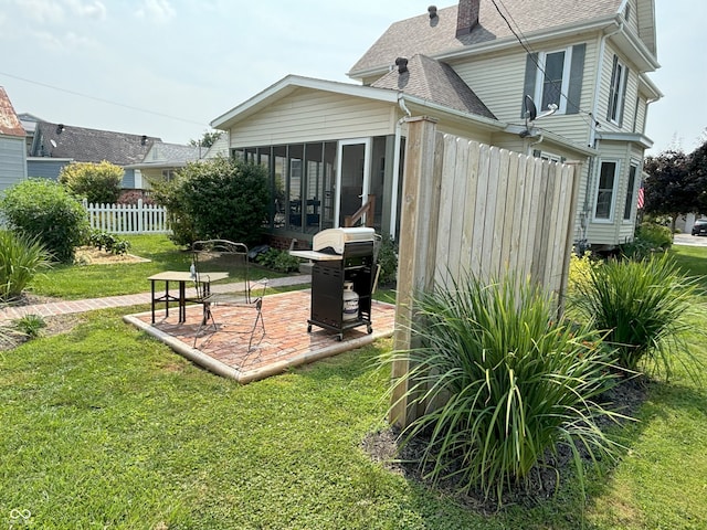 exterior space with fence, a yard, roof with shingles, a patio, and a sunroom