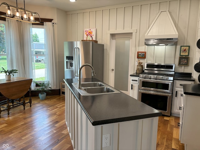 kitchen with stainless steel appliances, a sink, a healthy amount of sunlight, dark countertops, and custom range hood