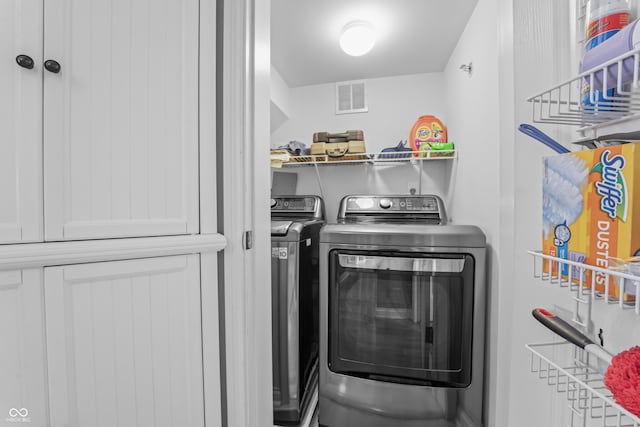 washroom with visible vents, laundry area, and washing machine and clothes dryer
