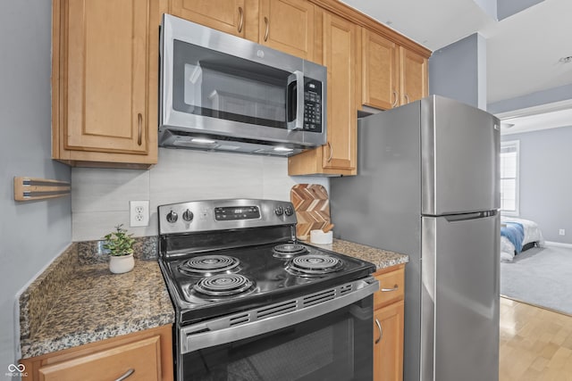 kitchen with stainless steel appliances, dark countertops, and light wood-type flooring