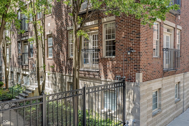 view of side of home featuring brick siding, a gate, and fence