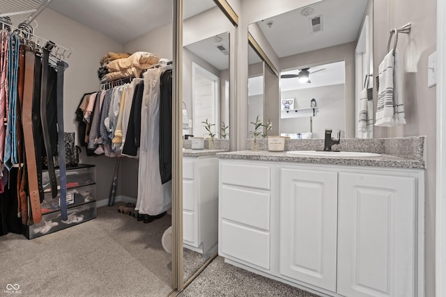 bathroom with vanity, carpet, and a walk in closet