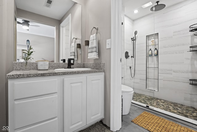 full bath with vanity, toilet, tiled shower, and visible vents