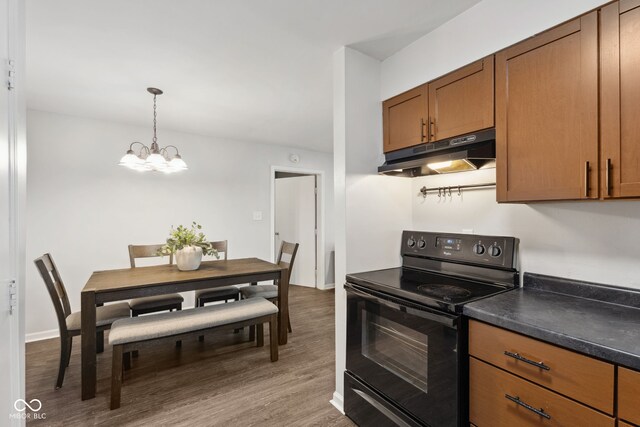 4464 Four Seasons Cir, Indianapolis, IN 46226 - kitchen featuring under cabinet range hood, dark countertops, wood finished floors, black electric range oven, and a notable chandelier