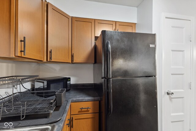 4464 Four Seasons Cir, Indianapolis, IN 46226 - kitchen with brown cabinetry, dark countertops, and black appliances