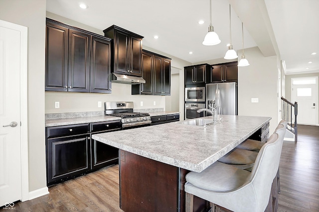13567 Moorcroft Dr, Fishers, IN 46037 - kitchen featuring stainless steel appliances, a sink, under cabinet range hood, light countertops, and wood finished floors