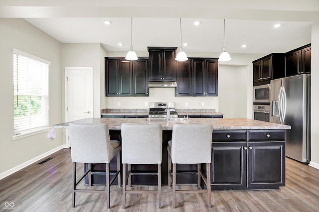 13567 Moorcroft Dr, Fishers, IN 46037 - kitchen with appliances with stainless steel finishes, a kitchen island with sink, under cabinet range hood, baseboards, and recessed lighting