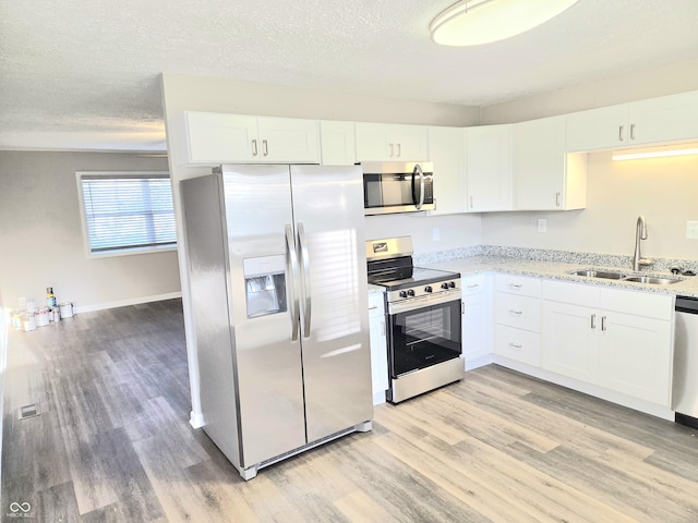 2465 N Eaton Ave, Indianapolis, IN 46219 - kitchen with stainless steel appliances, a sink, light wood finished floors, light stone counters, and white cabinetry