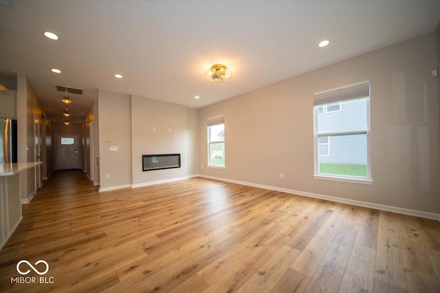 9455 Orchard Cove Dr, Indianapolis, IN 46239 - unfurnished living room with a glass covered fireplace, recessed lighting, baseboards, light wood-type flooring, and visible vents