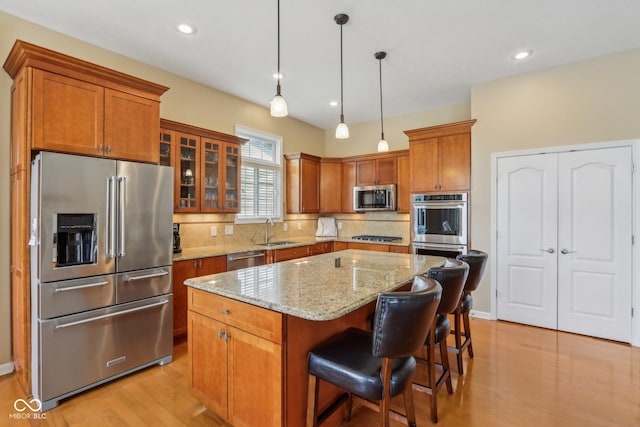 1361 Trescott Dr, Westfield, IN 46074 - kitchen featuring stainless steel appliances, a sink, brown cabinets, decorative backsplash, and a kitchen island
