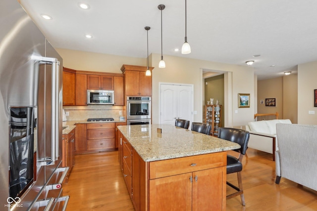 1361 Trescott Dr, Westfield, IN 46074 - kitchen with stainless steel appliances, a kitchen breakfast bar, light wood-style floors, a center island, and decorative backsplash