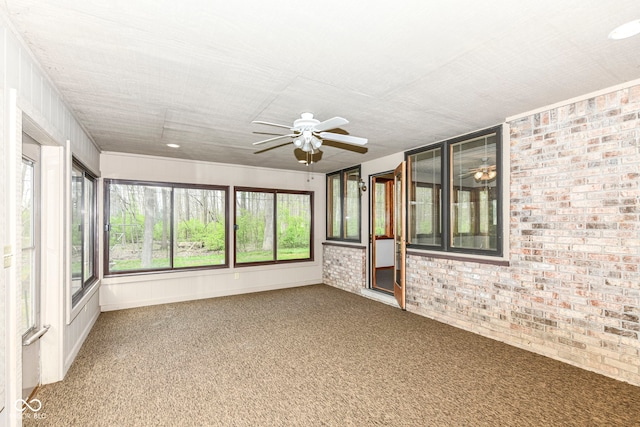 unfurnished sunroom featuring brick wall and carpet flooring