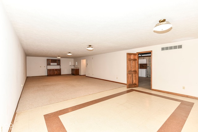 unfurnished living room with tile patterned floors, visible vents, and baseboards